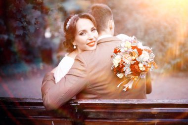 güzel genç gelin buketi çiçek ve yakışıklı Damat Düğün gününde parkta bankta oturmuş ile