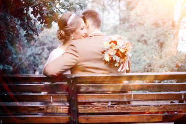 güzel genç gelin buketi çiçek ve yakışıklı Damat Düğün gününde parkta bankta oturmuş ile