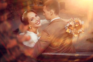 güzel genç gelin buketi çiçek ve yakışıklı Damat Düğün gününde parkta bankta oturmuş ile