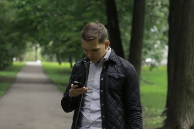 Yaz parkta Smartphone kullanarak yakışıklı genç 
