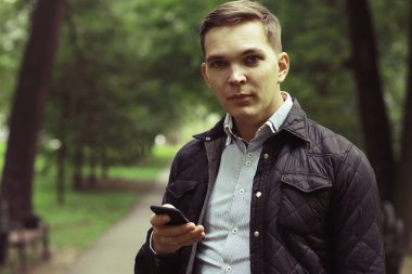 Yaz parkta Smartphone kullanarak yakışıklı genç 