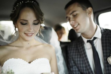 güzel genç gelin ve birlikte arabada oturan mutlu yakışıklı damat 