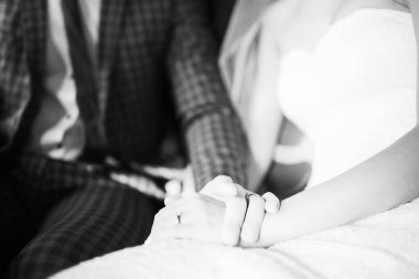 Genç gelin beyaz dresss ve birlikte oturan ve düğün gününde elele damat 