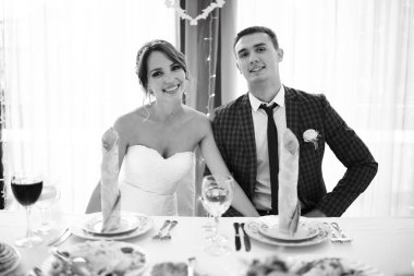 güzel genç gelin ve yakışıklı Damat Düğün gününde yemek masasında oturan 