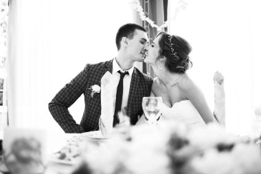 güzel genç gelin ve düğün gününde yemek masasında oturan ve öpüşme yakışıklı damat 