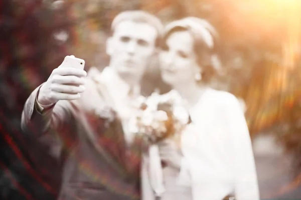 美丽的年轻新娘和英俊的新郎摆在夏季公园在婚礼的日子 并采取自拍 — 图库照片