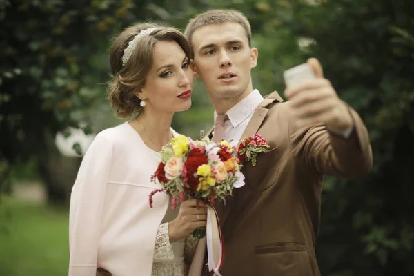 美しい若い花嫁とハンサムな新郎の結婚式の日と撮影 Selfie 夏の公園でポーズ — ストック写真