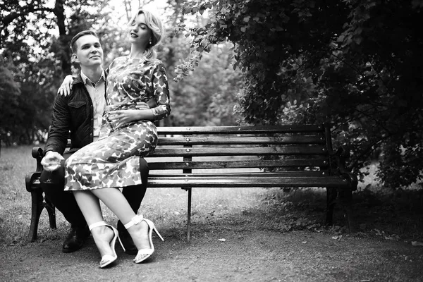 güzel genç kadın ve yakışıklı adam parkta bankta oturuyor. Çift tarihte tr açık, siyah ve beyaz 