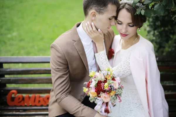 güzel genç gelin buketi çiçek ve yakışıklı Damat Düğün gününde parkta bankta oturmuş ile