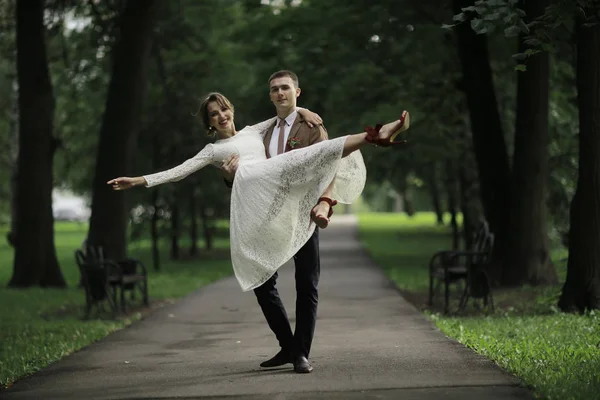白いドレスとハンサムな新郎の結婚式の日の夏の公園でポーズ美しい若い花嫁 — ストック写真