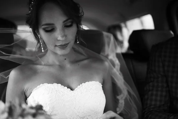 車に座っている白いウェディング ドレスで美しい若い花嫁の肖像画 — ストック写真