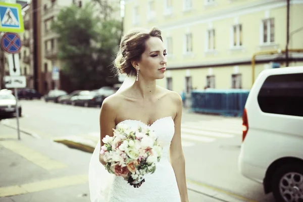 美丽的年轻新娘的画像在婚礼白色礼服摆在街上 — 图库照片