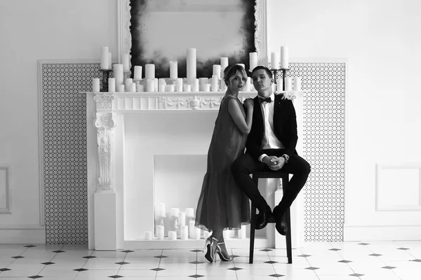 美しい若い女性とハンサムな男に合わせてキャンドル エレガントなインテリアと白い暖炉に近いポーズ — ストック写真