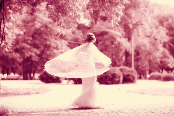 Beautiful bride in white wedding dress posing in autumn park