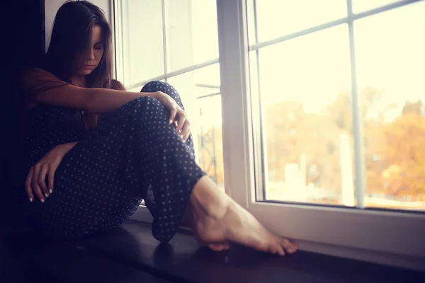 Mujer joven en alféizar de la ventana — Foto de Stock