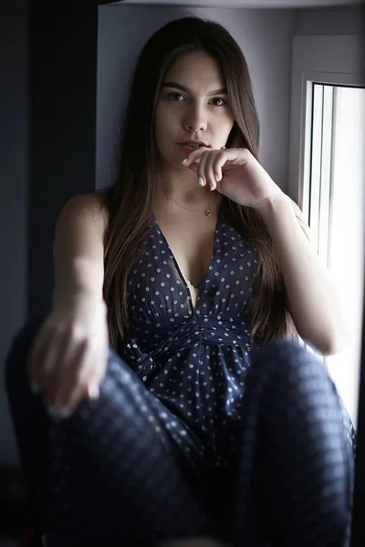 Mujer joven en alféizar de la ventana — Foto de Stock