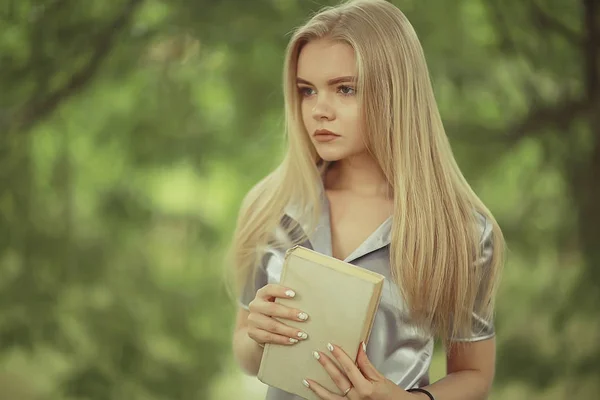Young woman holding book in park — Stock Photo, Image