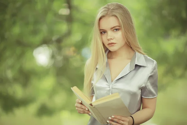 Молода жінка тримає книгу в парку — стокове фото