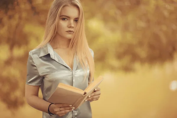 Junge Frau hält Buch im Park — Stockfoto