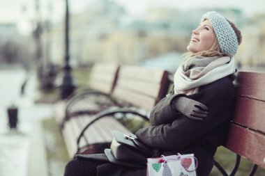 Genç kadın bankta oturuyor.