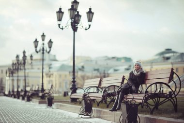 Genç kadın bankta oturuyor.