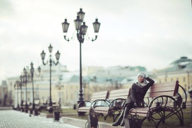 Genç kadın bankta oturuyor.