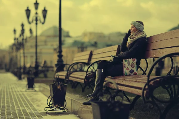 Genç kadın bankta oturuyor.