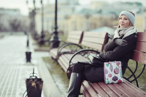 Genç kadın bankta oturuyor.