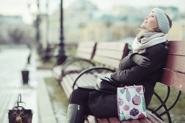 Genç kadın bankta oturuyor.