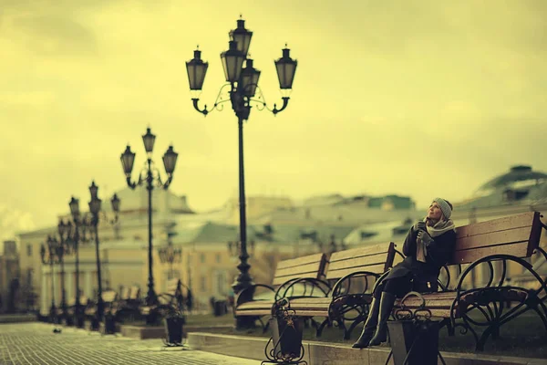 Genç kadın bankta oturuyor.