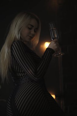 Seksi sarışın kız kadehten şampanya içiyor. Akşam gösterişli bir portreden.
