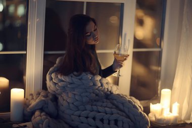 Pencerenin önünde battaniyede oturan kız, mumlar gece, yalnızlık, genç yalnız kız, stres