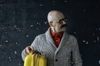 Adamın elinde bavul, turist konsepti, bıyıklı, gözlüklü, tuhaf bir tip var.