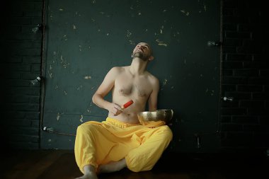 Tibet şarkı kasesi, sarı pantolonlu bir keşiş meditasyon yapar ve müzik kasesi, Budizm ve din çalar.