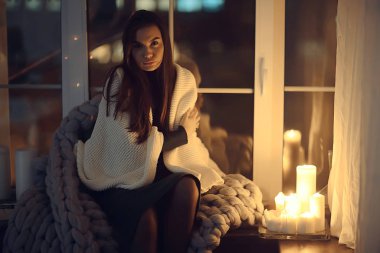 Pencerenin önünde battaniyede oturan kız, mumlar gece, yalnızlık, genç yalnız kız, stres