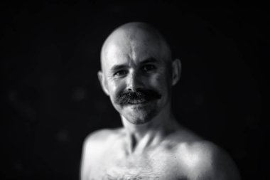 Bıyıklı neşeli kel adam, gülümseyen, poz veren, bıyıklı genç bir adamın portresi.