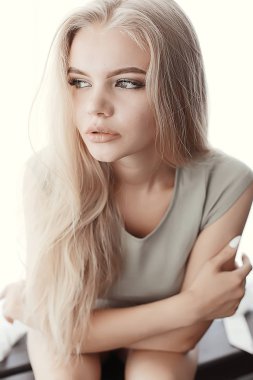Genç, sarışın, uzun saçlı, şık bir model stüdyoda poz veriyor.