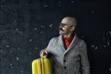 Adamın elinde bavul, turist konsepti, bıyıklı, gözlüklü, tuhaf bir tip var.