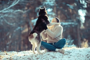 young man hugs a husky dog in the winter in the forest, a man and a dog hug together and play in a winter nature landscape