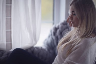 Kışın evin içinde, örnek bir kız pencerede örgü örüp güneşleniyor, evde soğuk bir gün.