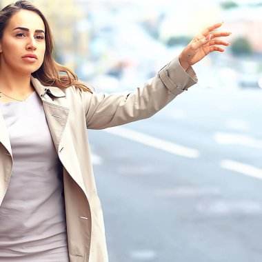 Kadın yolda bir araba yakalıyor, yetişkin genç bir kız taksi bekliyor, geçen bir aracı durduruyor, otostop çekiyor.