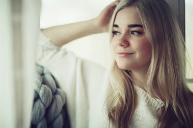 Ev cana yakın kız ekose pencere, ev sonbaharı görünümü, sıcak örgü örülmüş battaniyenin içindeki model ısınıyor.