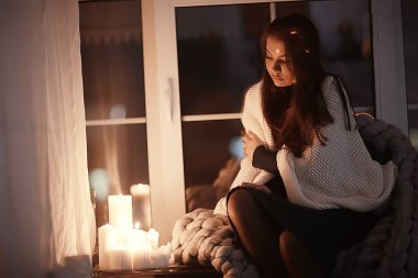 Pencerenin önünde battaniyede oturan kız, mumlar gece, yalnızlık, genç yalnız kız, stres