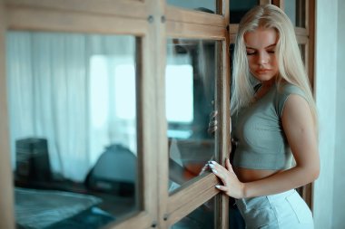 Çatı katında bir kız, modern bir ev, pencereler, duvar. Genç yetişkin pozu