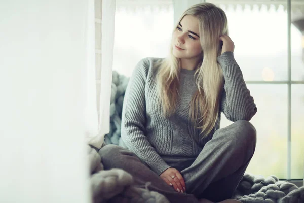 冬の家のインテリアモデルの女の子が窓の編んだ毛布に身を包んだ家の寒い日 — ストック写真