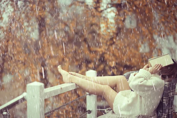 girl with a book in autumn rain on the veranda of the house, seasonal portrait romantic autumn with rain, weather raindrops