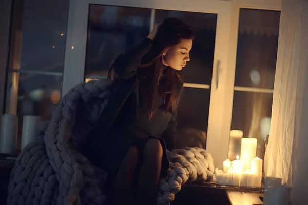 girl sitting in a blanket at the window, candles night, loneliness, young lonely girl, stress