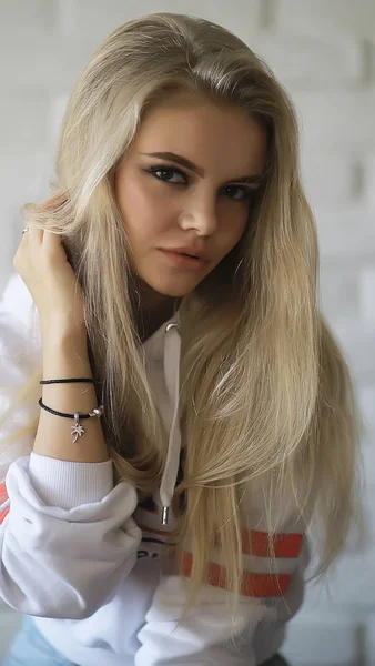 young adult blonde long hair at home, stylish model posing in the studio