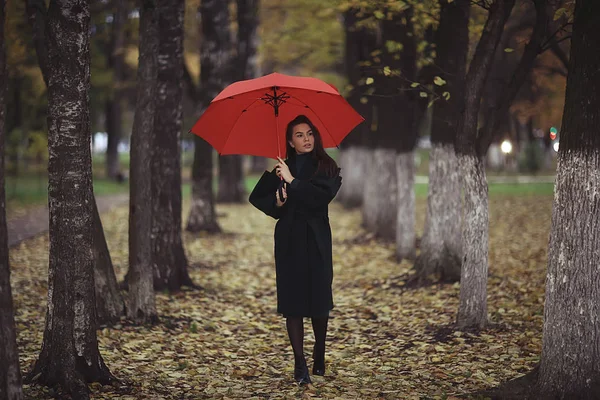 autumn evening woman holds umbrella, october in dark city park, young lonely model with umbrella