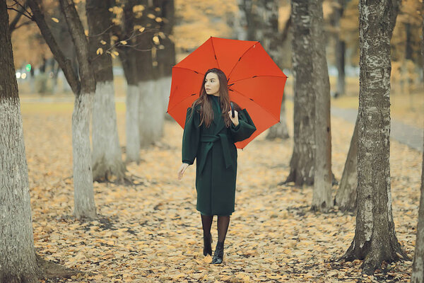 Autumn evening woman holds umbrella, october in dark city park, young lonely model with umbrella